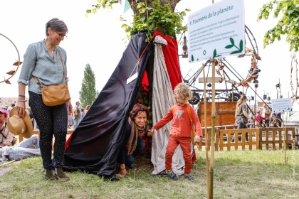 photo d’une femme et d’un enfant sortant d’une cabane en tissus accrochée autour d’un platane